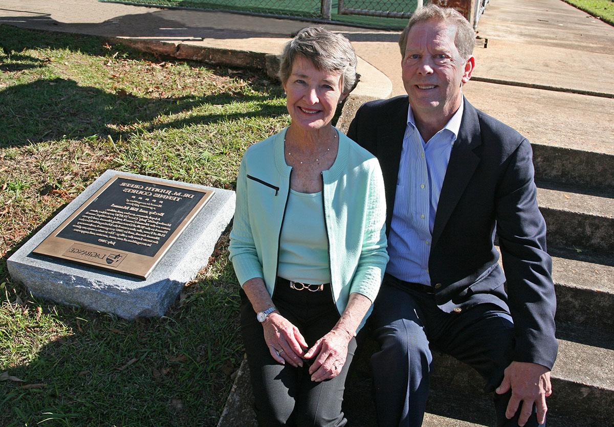 Bill and Becky Manuel sit on a hill next to their dedication plaque.